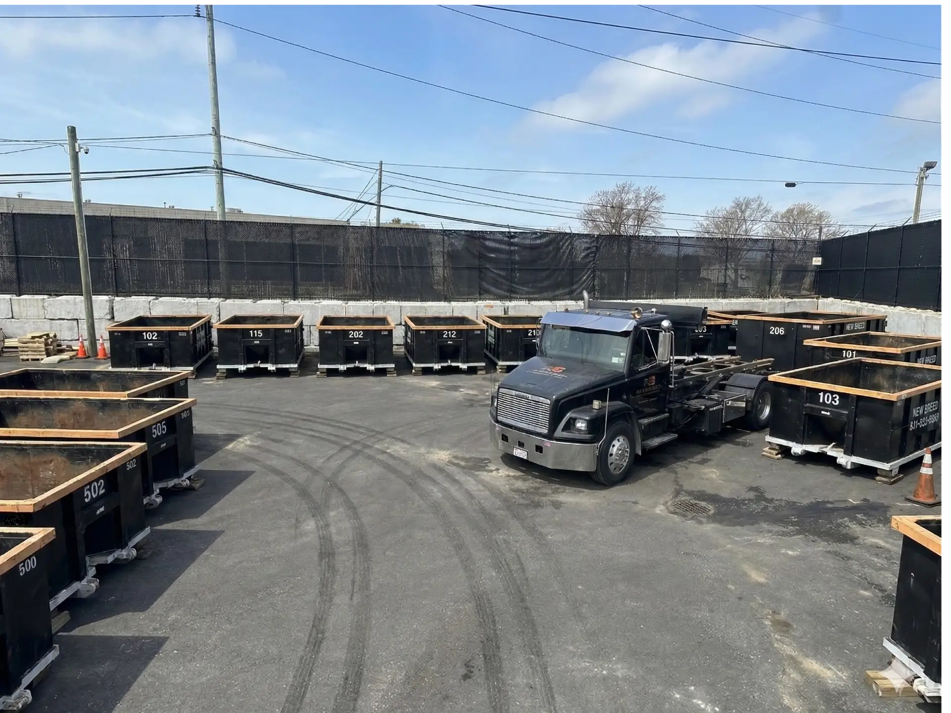 New Breed Haulage roll-off containers and cable hoist truck in our Long Island equipment yard
