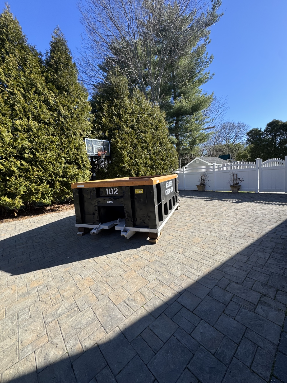 10-Yard Dumpster with Driveway Protection A 10-yard New Breed Haulage dumpster placed safely on wood planks to protect a paver driveway.